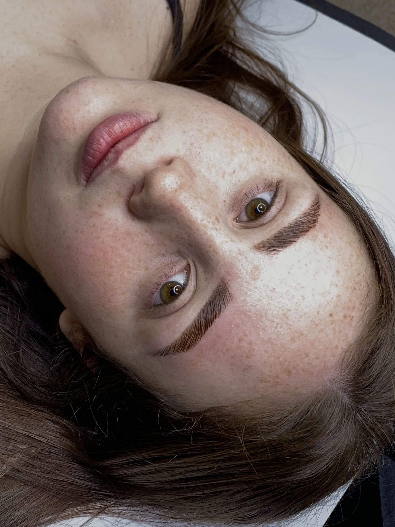 Sobrancelhas escuras e preenchidas com fios marcados, vistas de perto